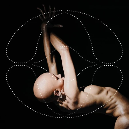 Dramatic studio shot of a bald woman in dynamic pose, arms raised, body arched, adorned with geometric dot pattern against a black background.