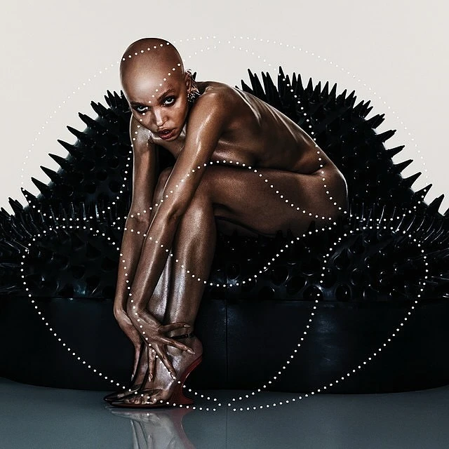 Striking art photo features a posed, bald adult woman with bronze skin seated on a black spiked surface with a dotted overlay.
