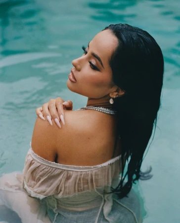 A woman with long dark wet hair wearing an off-shoulder top in turquoise water, photographed by Josefina Santos