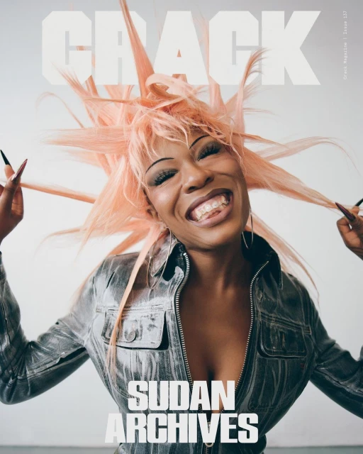 Crack Magazine cover featuring a woman with coral hair wearing a grey jacket, smiling with her hands up near her head.