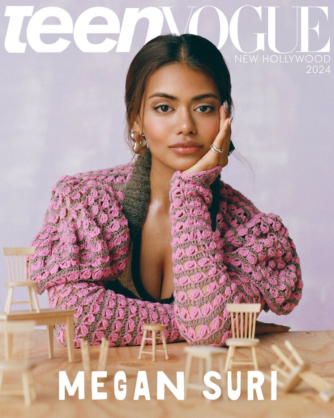 Teen Vogue cover featuring model Megan Suri in a pink crocheted cardigan, seated with miniature wooden chairs, against a soft lilac background.