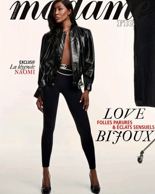 Fashion editorial shot of an adult woman with long dark hair wearing a black jacket and leggings, posing against a neutral backdrop.