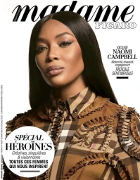 Naomi Campbell with long dark hair wearing a patterned plaid blouse in a magazine cover portrait.