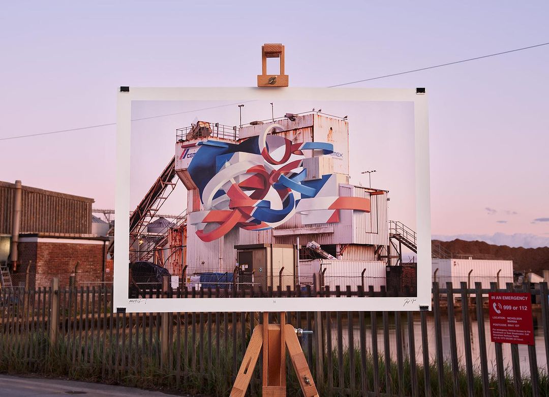 Outdoor photograph of a building with graffiti art mounted on an easel in front of a pond, captured during the warm light of the sunset.