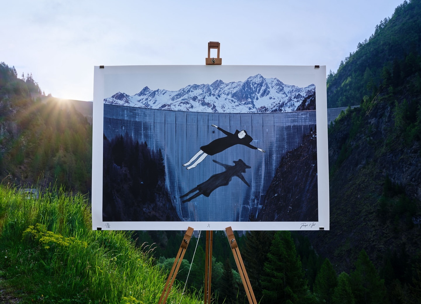 Conceptual art piece displayed outdoors features figures floating against a dam and mountain backdrop, evoking a surreal and contemplative mood.