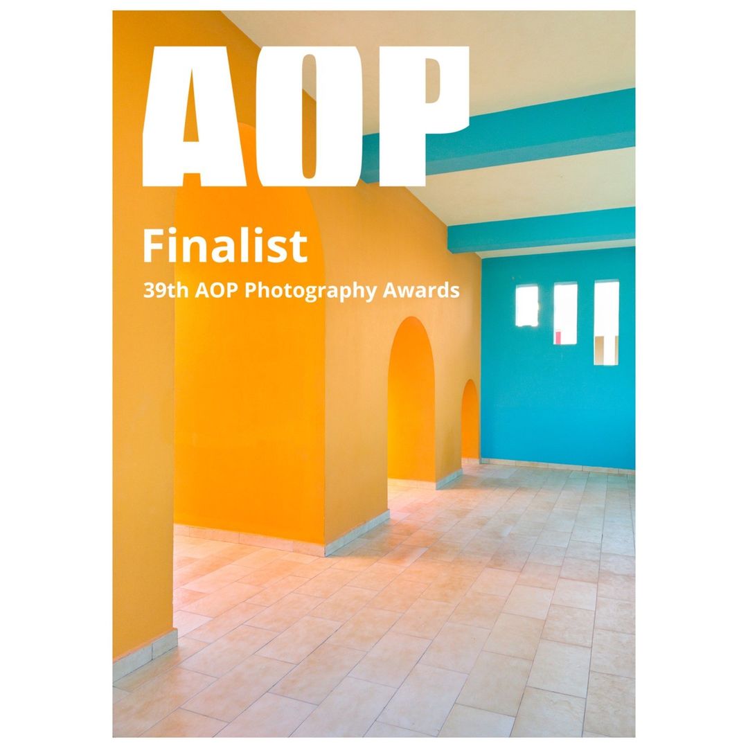 Interior of an empty room with orange and turquoise walls and beige tile floors, designed for the 39th AOP Photography Awards.