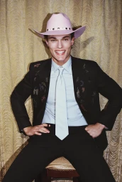 Smiling man in black suit with pink cowboy hat and light blue shirt photographed by Zuzanna Blur