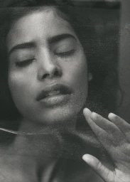 Close-up monochrome portrait of a woman with closed eyes and hand near her face, shot through a textured veil by Zuzanna Blur