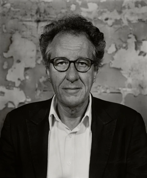 Portrait of Geoffrey Rush in dark blazer and white shirt against textured wall, by Shanahan in Sydney.