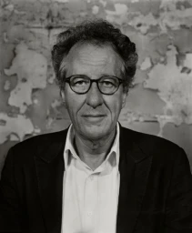Portrait of Geoffrey Rush in dark blazer and white shirt against textured wall, by Shanahan in Sydney.