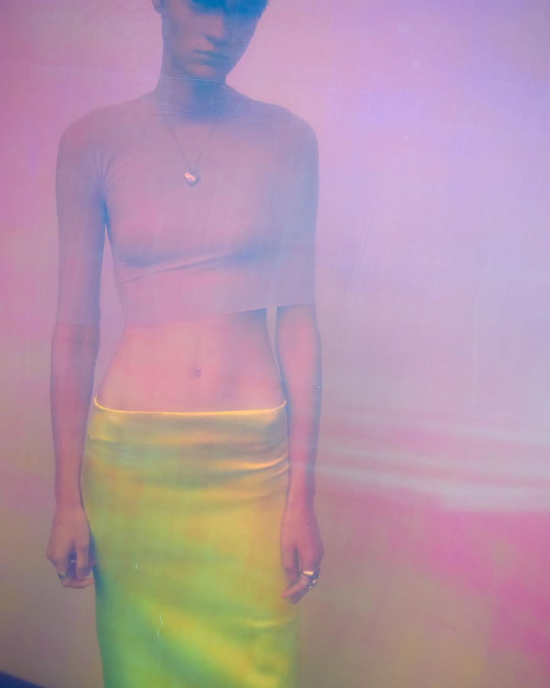 Model wearing a sheer top and yellow skirt captured in soft pink and purple light by Josephine Lochen in Paris