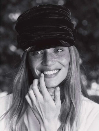 Close-up portrait of a smiling woman with freckles wearing a dark captain hat by Josephine Lochen