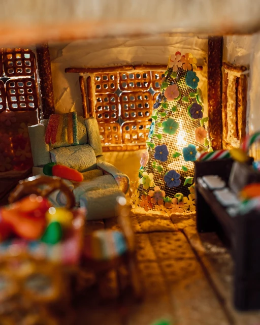Detailed gingerbread house interior featuring festive decorations, a cozy chair, and warm lighting, evoking a whimsical holiday scene.
