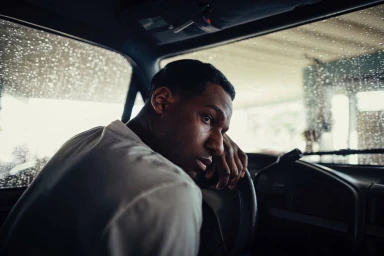 A man looking back over his shoulder from the driver seat of a car during a rainy day, photographed by Josh Goleman.