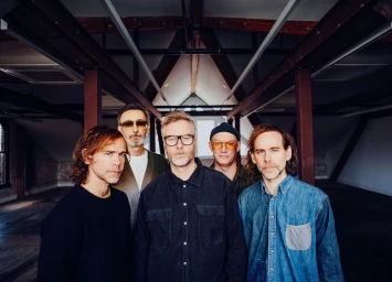 Five men standing together in an industrial loft space photographed by Josh Goleman in New York.