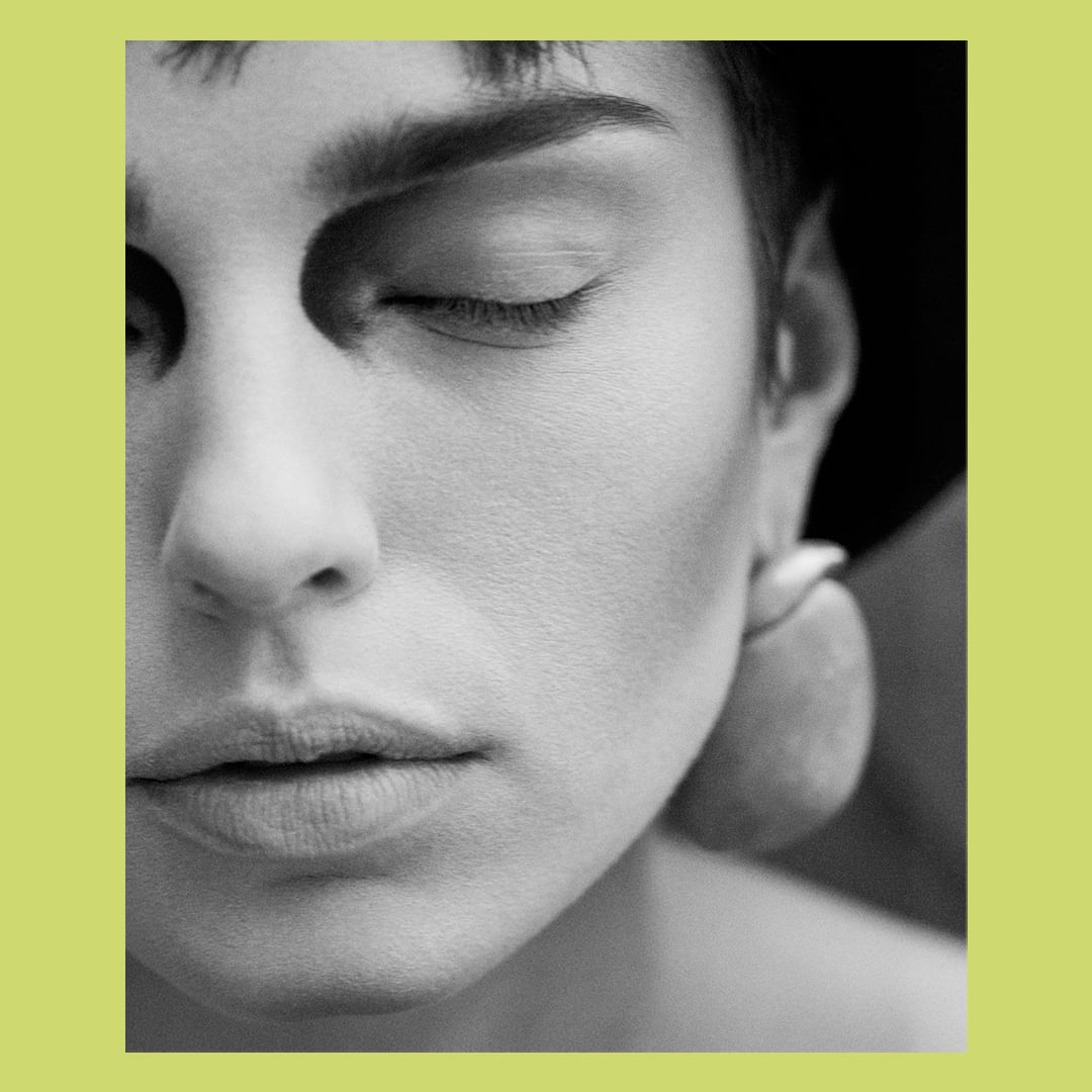 Monochrome portrait of a woman with closed eyes, featuring soft lighting and focus on her facial features and smooth skin texture.