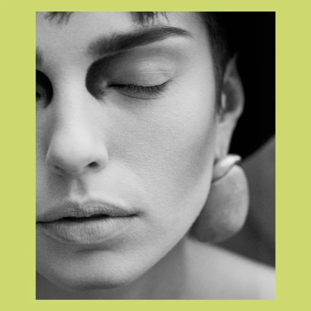 Monochrome portrait of a woman with closed eyes, featuring soft lighting and focus on her facial features and smooth skin texture.