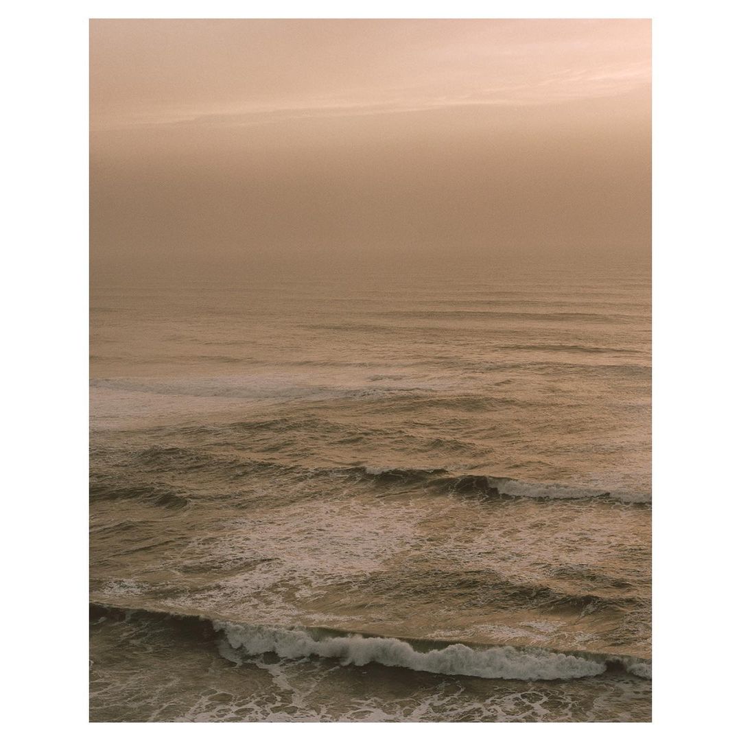 Scenic ocean view with waves and a golden sky. The water surface is textured with wave patterns, creating a serene atmosphere.