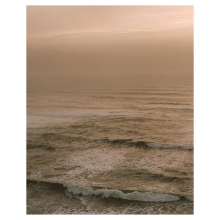 Scenic ocean view with waves and a golden sky. The water surface is textured with wave patterns, creating a serene atmosphere.