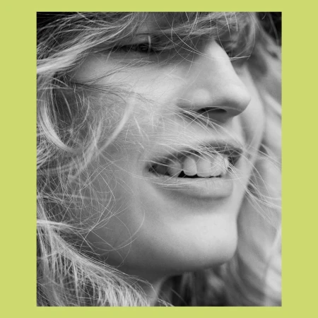 Close-up black and white portrait of a smiling woman with blowing hair framed by a chartreuse border