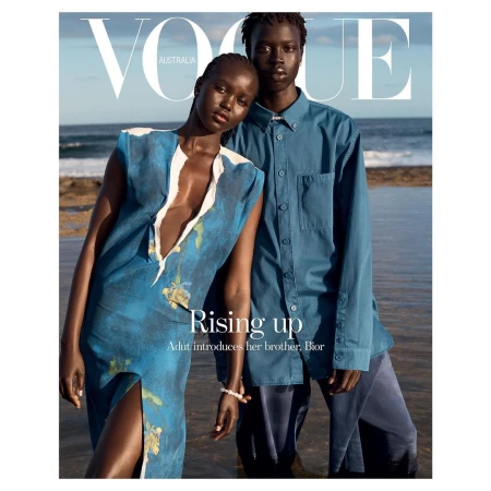 Vogue Australia cover featuring a woman in a blue dress and a man in a blue button-down shirt standing on a beach with water and sky.
