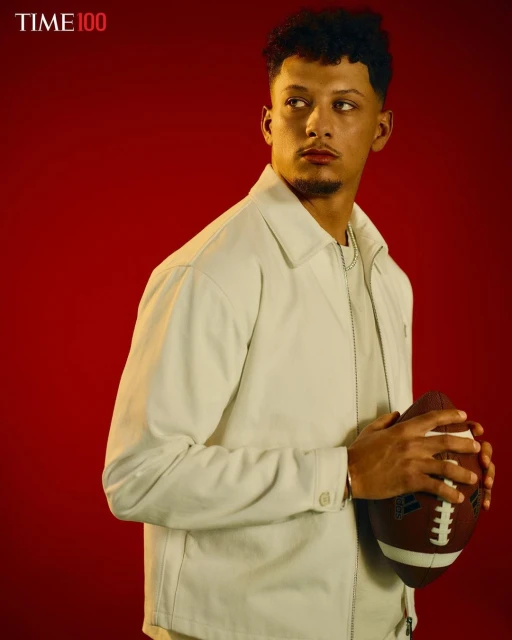 Portrait of football player Patrick Mahomes in light jacket holding football against red backdrop. Image promotes the Time 100 list.