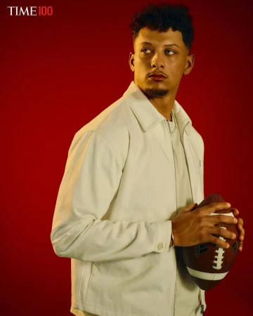 Portrait of football player Patrick Mahomes in light jacket holding football against red backdrop. Image promotes the Time 100 list.