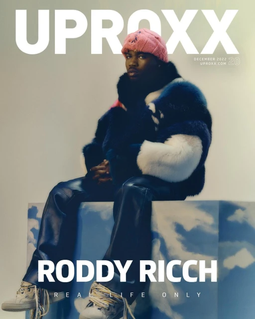 Magazine cover featuring Roddy Ricch wearing a colorful fur coat and pink beanie, sitting on a block with cloudy sky graphics.
