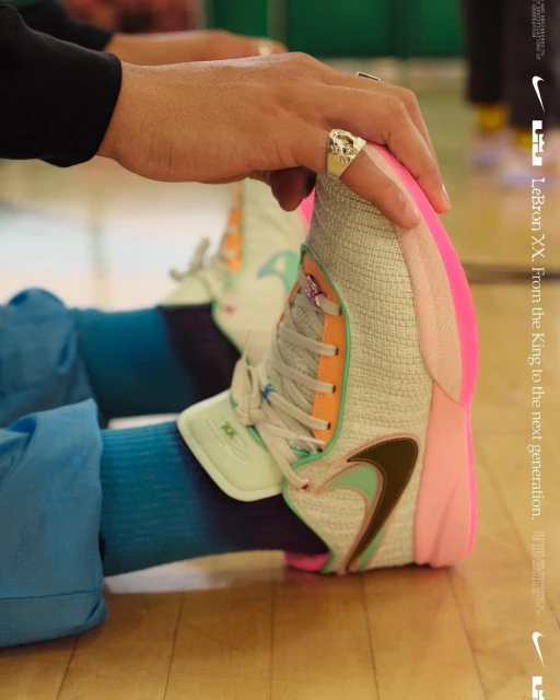 Close-up of a person's hand resting on a modern sneaker with blue gradient socks, Nike logo on side, and brand messaging visible.