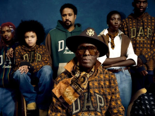 Group portrait of six people wearing apparel with 'DAP Harlem' emblem, set against a blue backdrop in a studio setting.