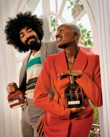 Two models holding liquor bottles by arched window, photographed by Joshua Kissi