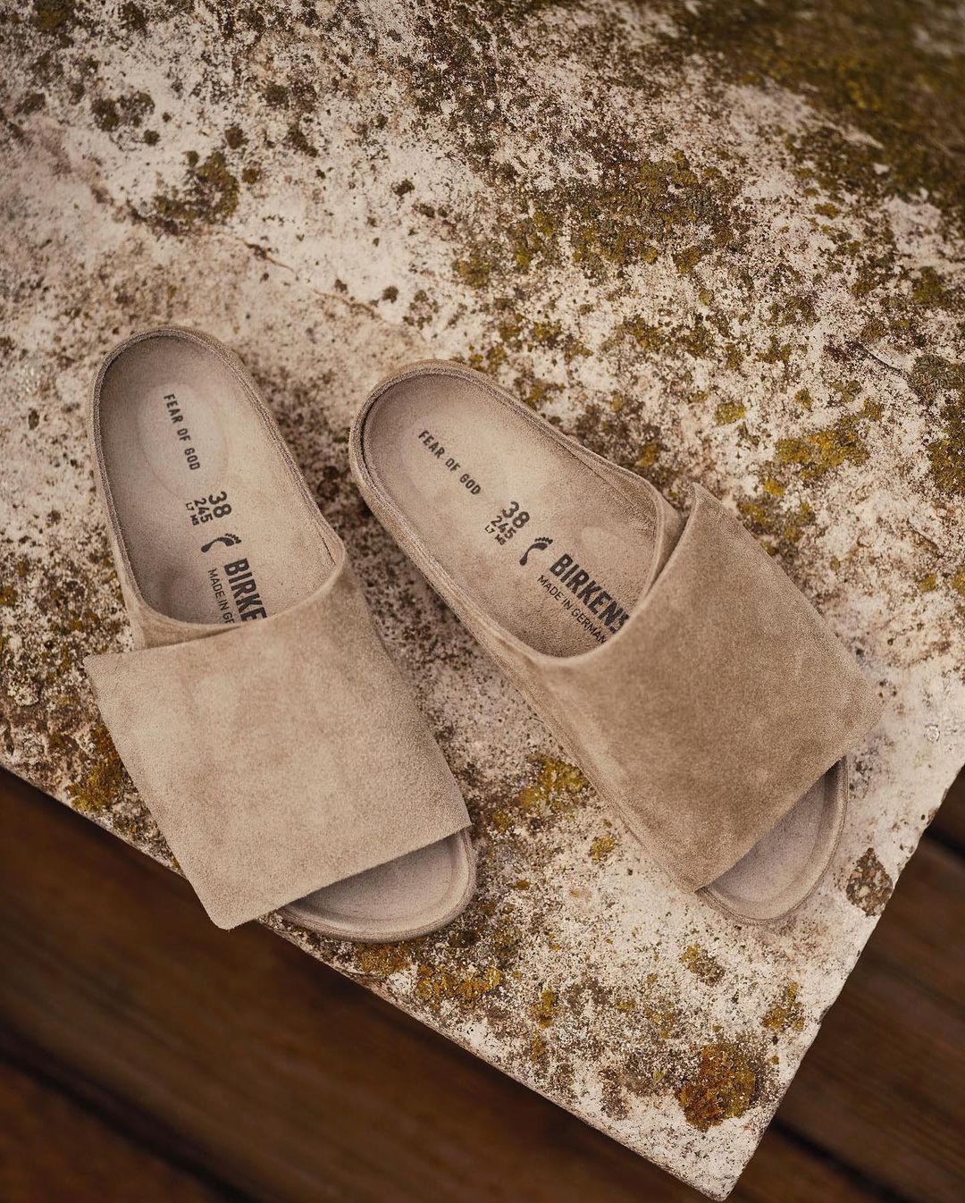 Neutral tone photo featuring a pair of suede Birkenstock clogs on a textured concrete surface, showcasing minimalist footwear design.