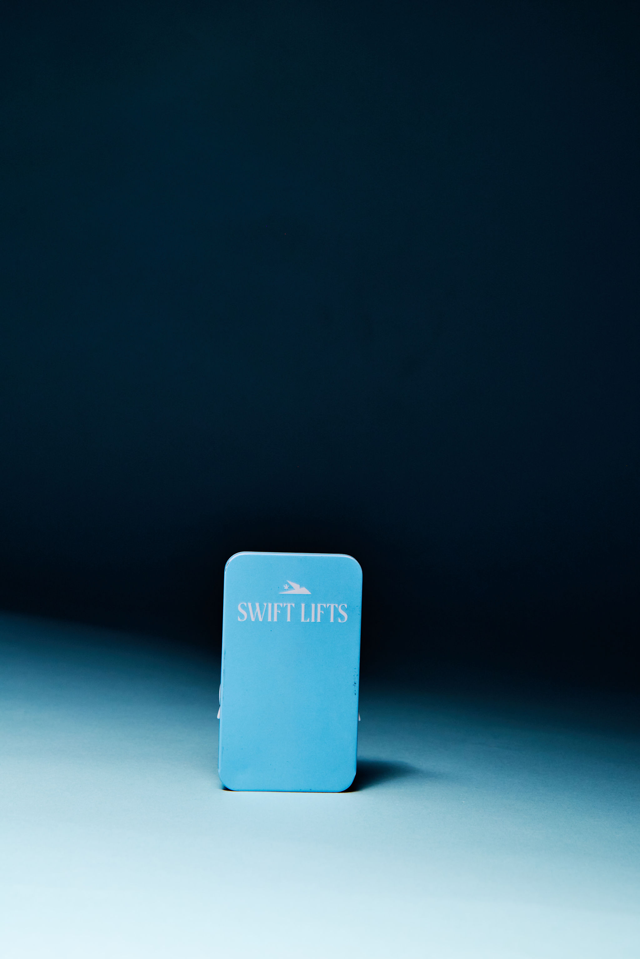 Product shot of a light blue box with 'Swift Lifts' text, set against a gradient dark blue background and soft, directional lighting.