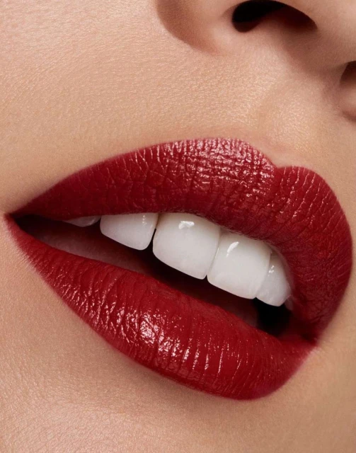 Close-up of a woman's face featuring red lipstick on her lips and visible white teeth, emphasizing beauty and makeup for fashion.
