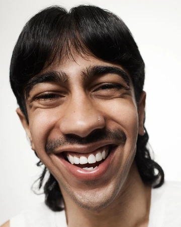 Close-up portrait of a smiling man with dark hair and a mustache against a plain white background by photographer Joshua Pestka