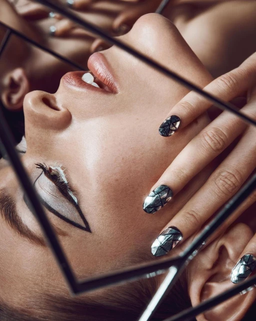 Artistic beauty shot of a woman with geometric makeup and metallic nail art. Framed by geometric shapes, close-up on face.