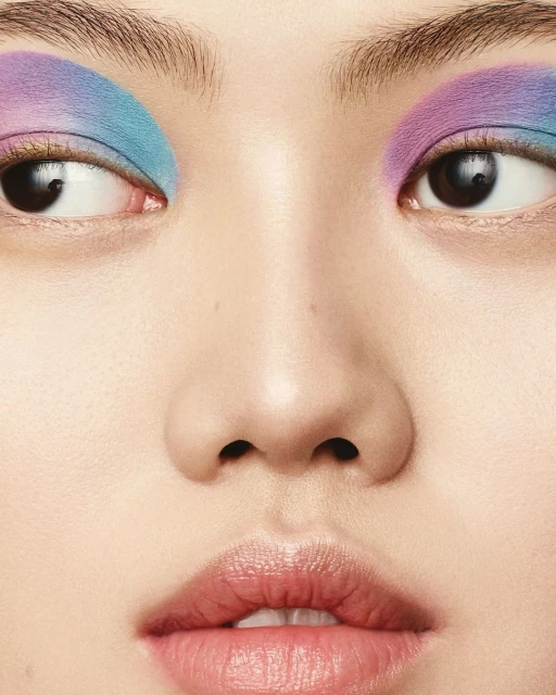 Close-up of a woman's face featuring vibrant blue and purple eyeshadow, highlighting the eye makeup in a beauty and fashion context.