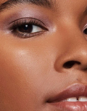 Close-up portrait of a Black woman featuring purple eyeshadow and glossy lips photographed by Joshua Pestka