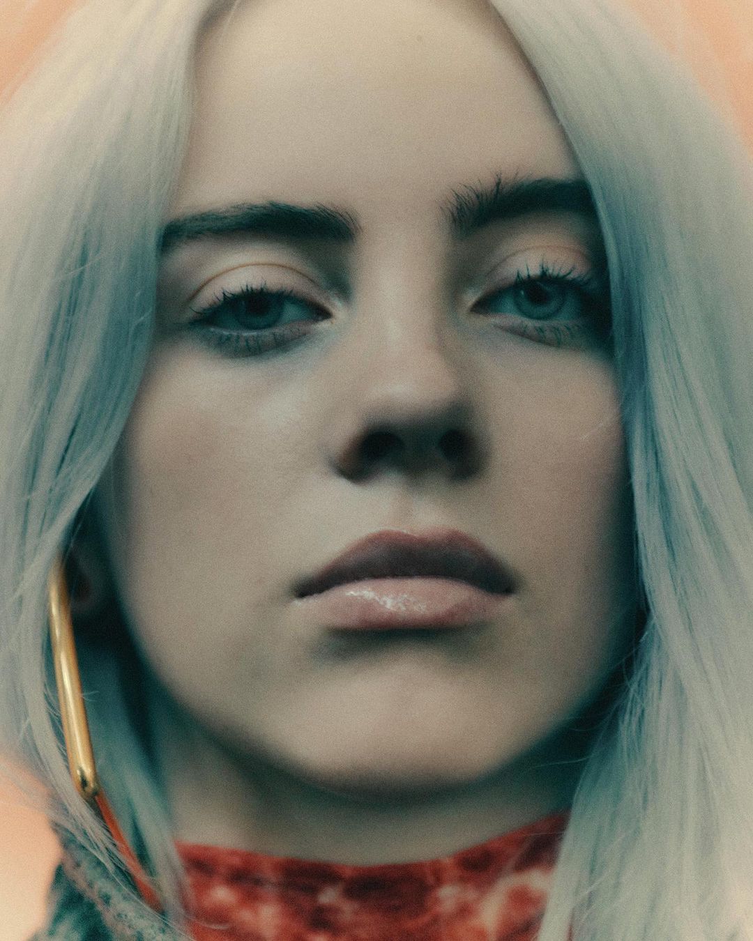 Close-up portrait of a young woman with light-colored hair and green eyes looking directly at the camera in a studio setting.