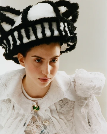 Model wearing a fuzzy black and white hat and a white lace blouse photographed by Joyce Ng in London