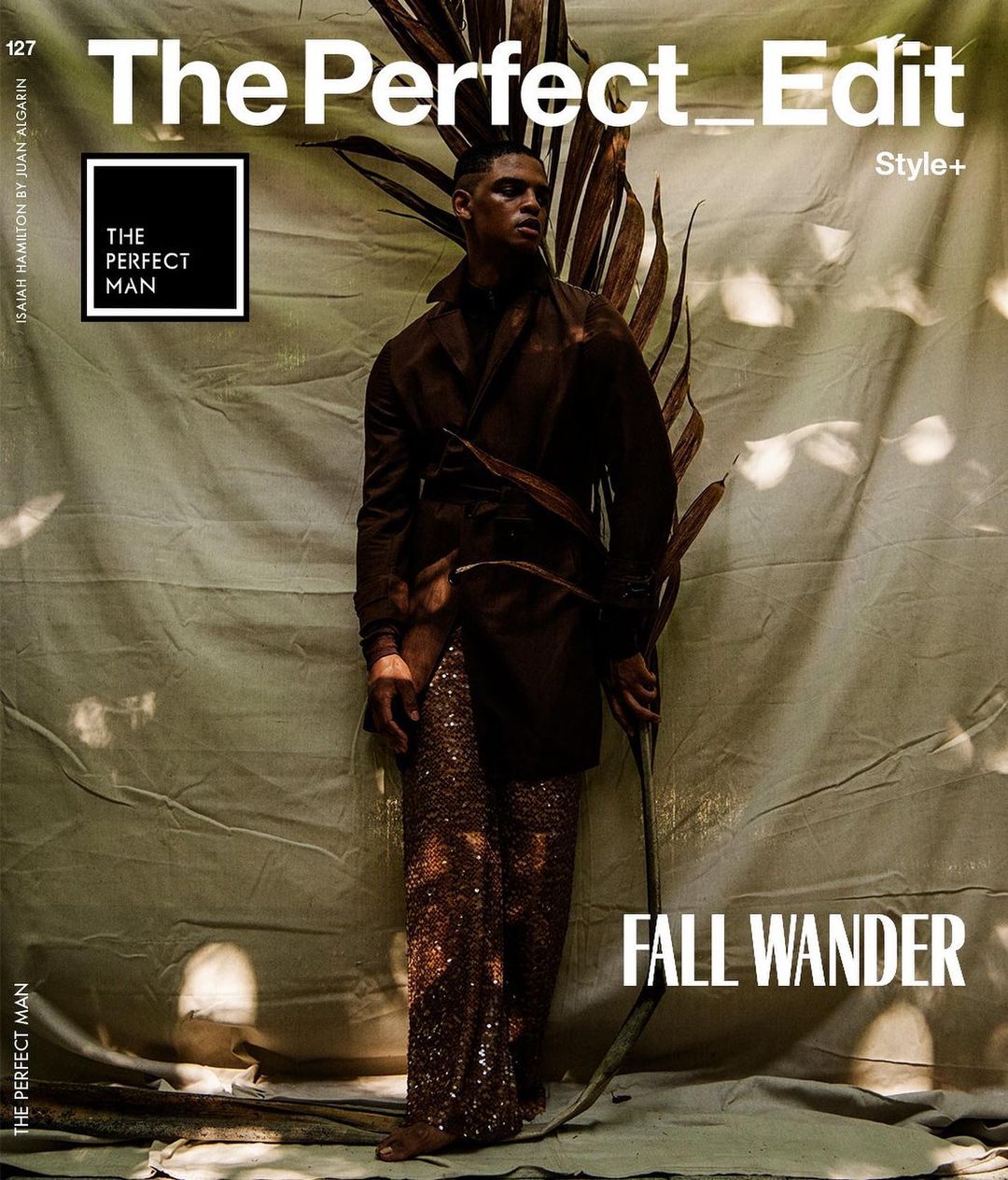 Magazine cover featuring a dark-skinned male model in a brown coat and sequined pants holding a large dried palm frond. The Perfect Man.