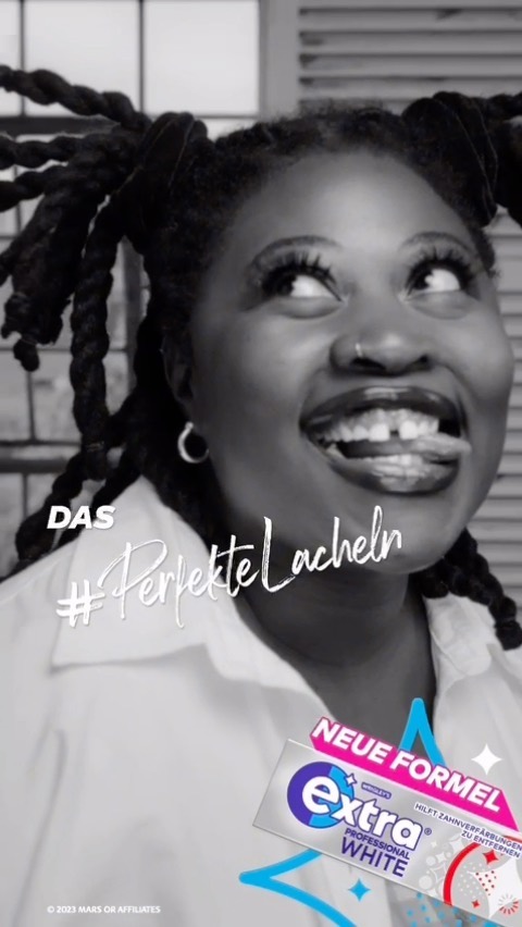 Close-up portrait of a smiling black woman with braided hair, wearing a white shirt, with Extra White chewing gum pack in the foreground.