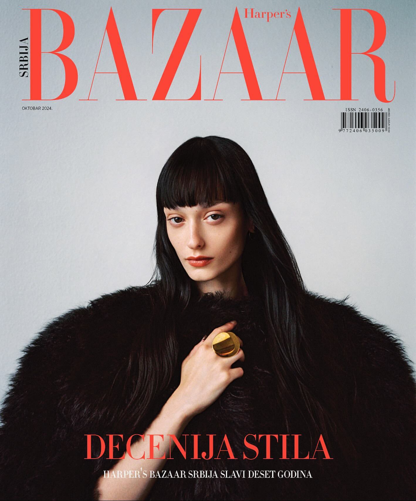Harper's Bazaar Serbia cover featuring a woman with dark hair wearing a black fur coat and a gold ring, against a light gray backdrop.