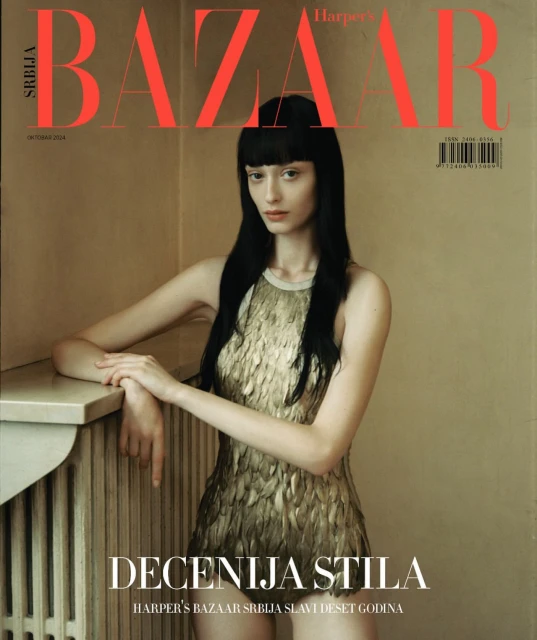 Harper's Bazaar Srbija magazine cover featuring a young woman in a gold dress, posing near a radiator in a neutral-toned room.
