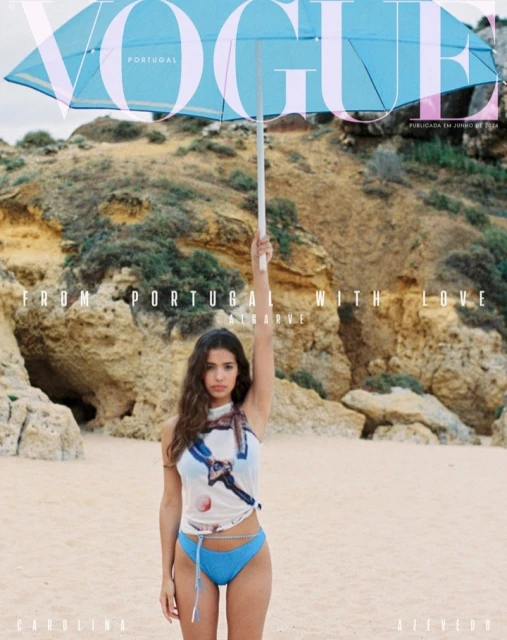 Vogue Portugal cover featuring a young woman in a blue bikini holding a blue umbrella on a sandy beach with a rocky background.