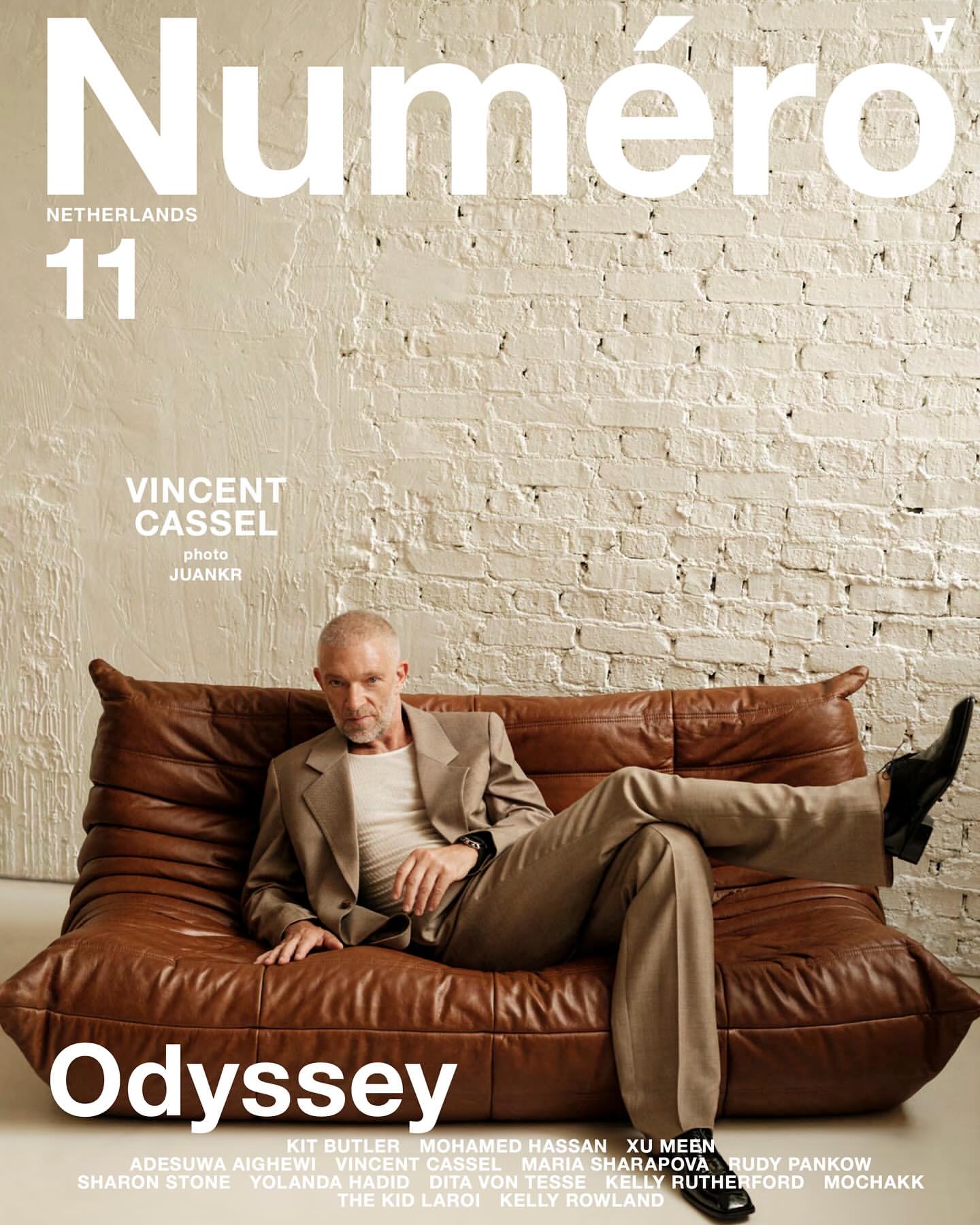Magazine cover features Vincent Cassel reclining on a brown leather sofa in a beige suit. The cover includes the magazine's title.