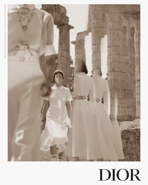 Fashion editorial featuring models in white dresses at ancient ruins, showcasing a blend of modern fashion with historical architecture in sepia.
