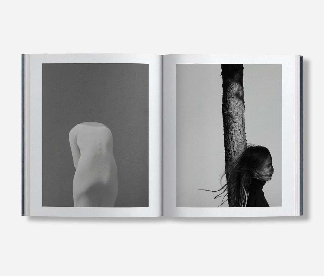 Monochrome book spread showcasing a sculpture of a human torso and a profile view of a person next to a tree trunk.