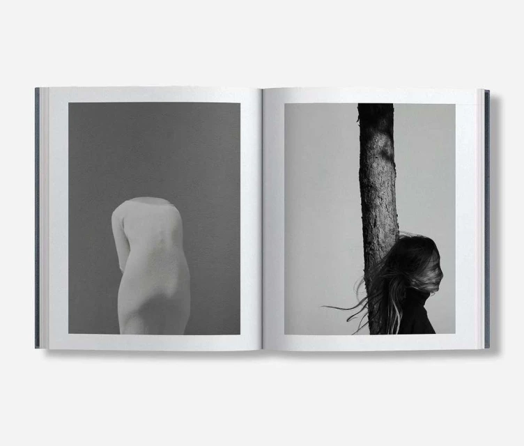 Monochrome book spread showcasing a sculpture of a human torso and a profile view of a person next to a tree trunk.