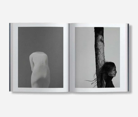 Monochrome book spread showcasing a sculpture of a human torso and a profile view of a person next to a tree trunk.